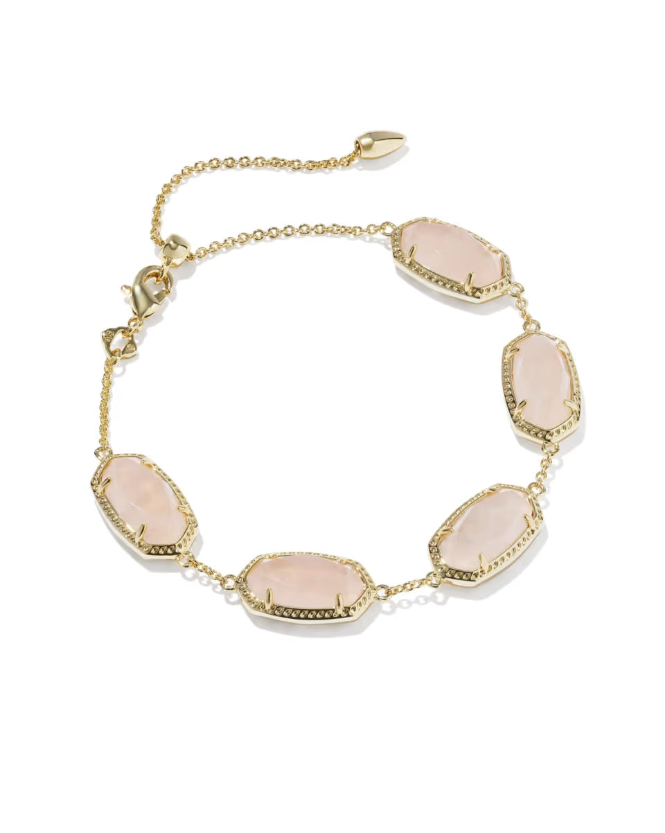 The Elaina Gold Link Bracelet in Rose Quartz by Kendra Scott features five rectangular pale pink rose quartz stones framed in gold and evenly spaced on a gold chain, with an adjustable sliding bead clasp. Available in one size with adjustable fit.