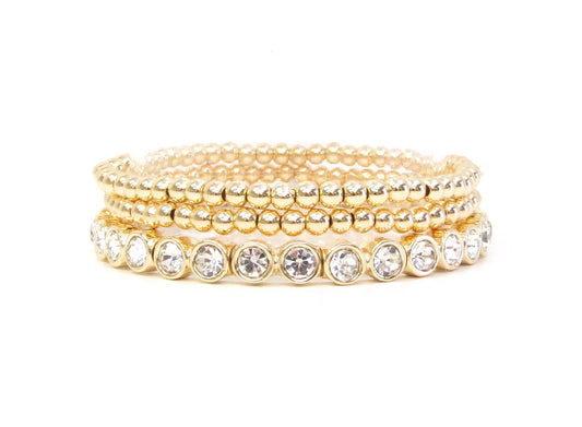 Logan Multi Strand Diamond Stretch Bracelet Stack: Four gold beaded bracelets, including one with clear round gemstones in bezel settings. Available sizes: S, M, L.