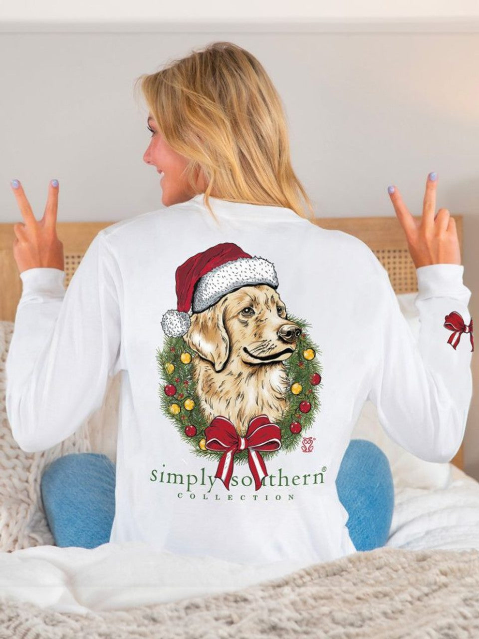 Merry and Bright Dog White Long Sleeve Shirt with golden retriever in Santa hat and Christmas wreath graphic, featuring a small red bow on the left sleeve. Available in multiple sizes.