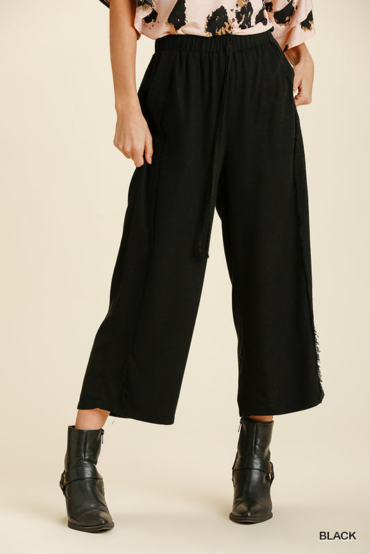 Then frayed edge wide leg pants that have front pockets are black with a drawstring waist