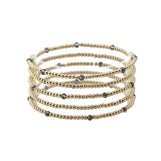 The Merl Gold & Colored Bead Accent Stretch Bracelet Stack features five coils of gold and dark gray beaded wrap design. Sizes available: One size fits most.