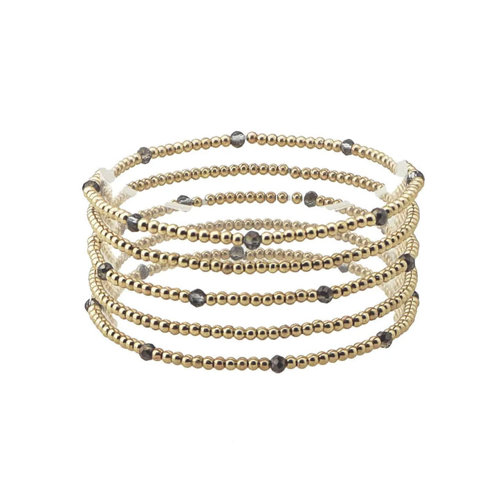 The Merl Gold &amp; Colored Bead Accent Stretch Bracelet Stack features five coils of gold and dark gray beaded wrap design. Sizes available: One size fits most.