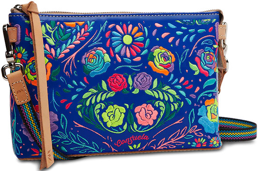 The Consuela Midtown Crossbody, Mango showcases floral embroidery with roses, daisies, and greenery on a bright blue background. It features an adjustable multicolored strap and tan leather accents. Available in one size.