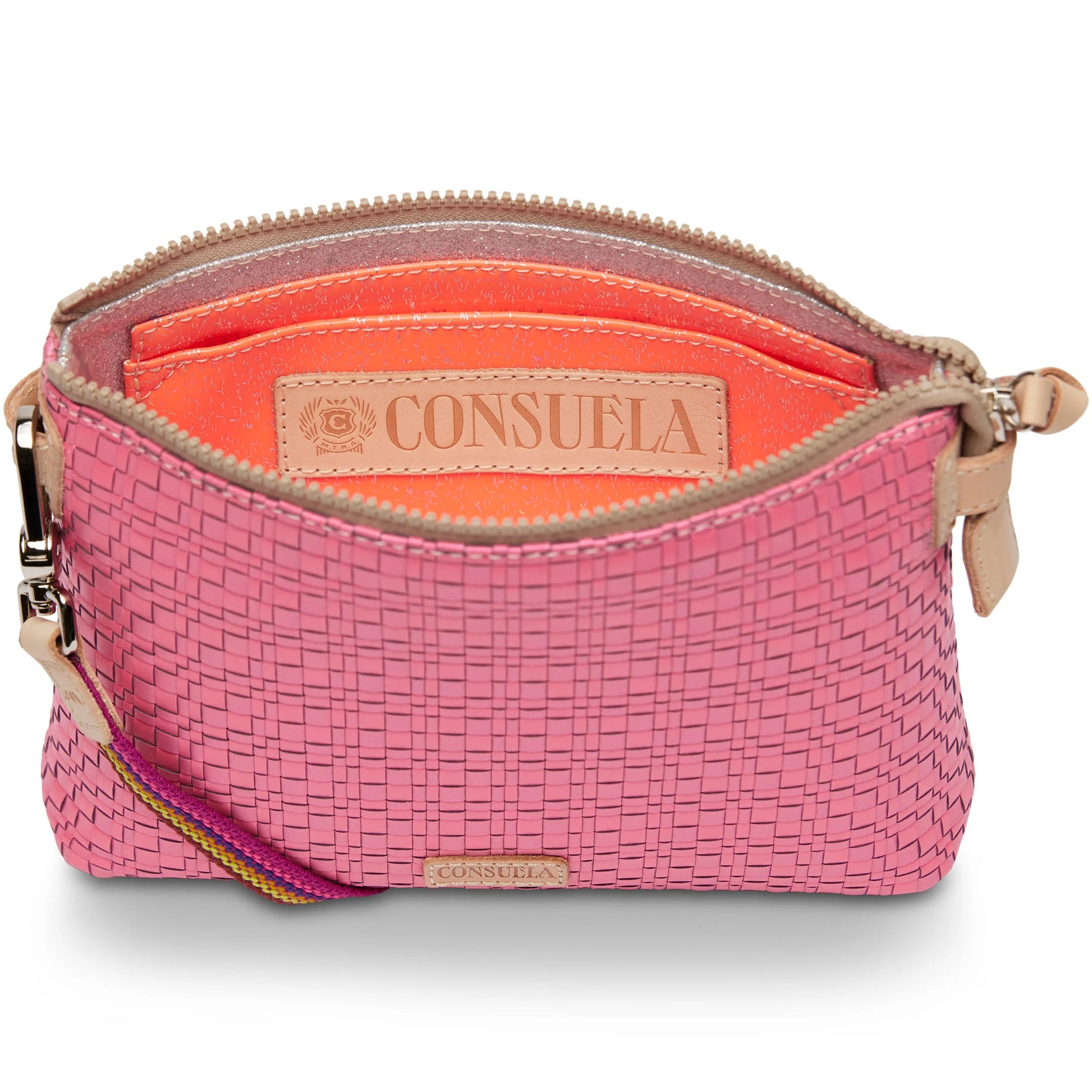 The Midtown Crossbody, Pink is a small woven pouch with a beige zipper, orange interior, wrist strap, and tan "CONSUELA" label inside. Available size: 7" L x 5" H x 2½" D with 6¾” drop.