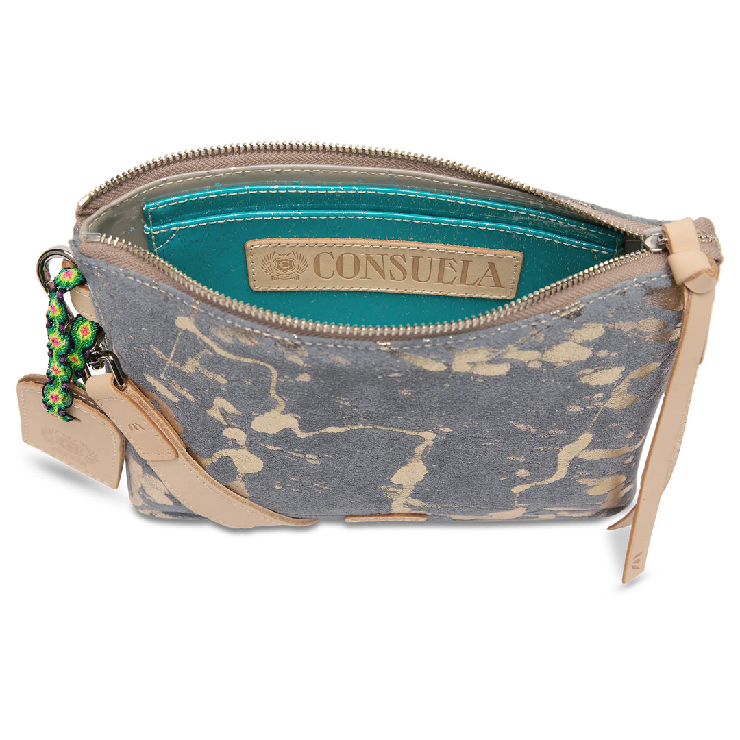 Gray and beige splatter pattern crossbody with tan leather zipper pull, turquoise interior, attached keychain accessories, and detachable strap. Available in one size.