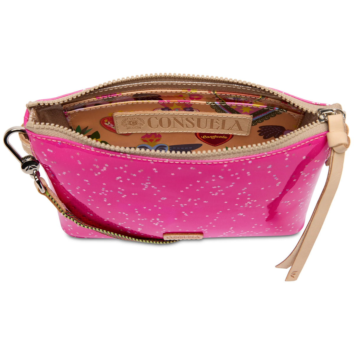 The Midtown Crossbody, Berry is a small pink wristlet with white speckles, a beige zipper, and tan leather strap. Convertible to a crossbody with an adjustable strap. Interior features a floral pattern and stitched Consuela logo patch. Sizes available: small.