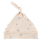 Beige cotton knotted hat for babies with black-outlined white circular cotton flower patterns. Features a folded brim. Available in sizes: Newborn, 0-3 Months, and 3-6 Months.