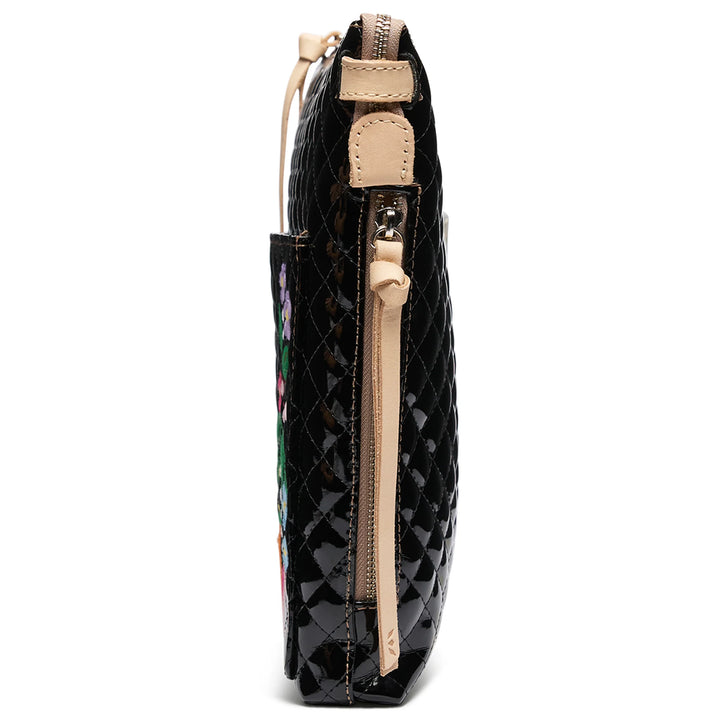 Side view of Tour Crossbody, La Reina—shiny black quilted clutch with tan zipper, leather accents, floral embroidery. Sizes: S, M.