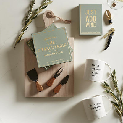 The "Here for the Charcuterie" set features acacia-handled cheese knives, themed napkins, mugs with witty wine-related phrases, an olive branch, and a wine opener. Sizes: Standard.