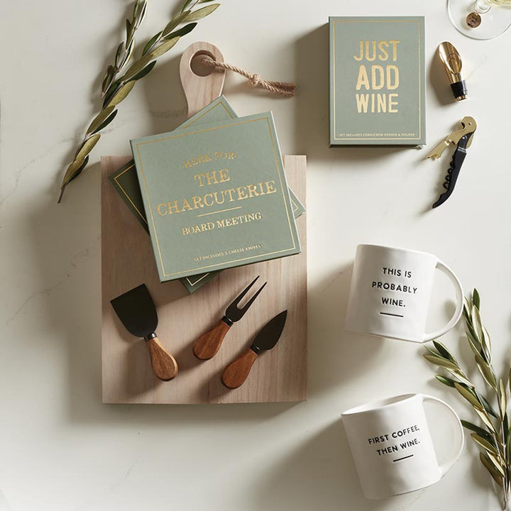 The "Here for the Charcuterie" set features acacia-handled cheese knives, themed napkins, mugs with witty wine-related phrases, an olive branch, and a wine opener. Sizes: Standard.
