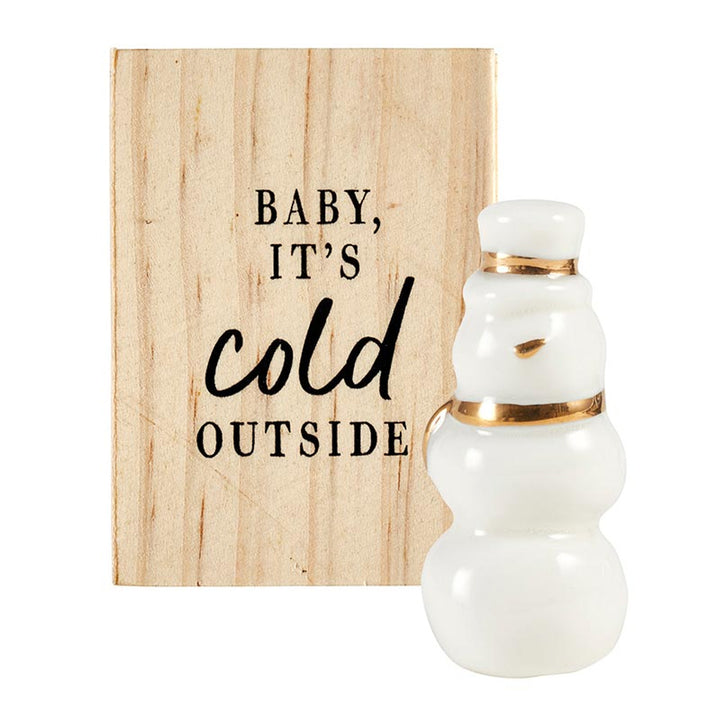 White snowman ceramic figurine with gold accents and a pine wood box printed with “BABY, IT’S COLD OUTSIDE.”.