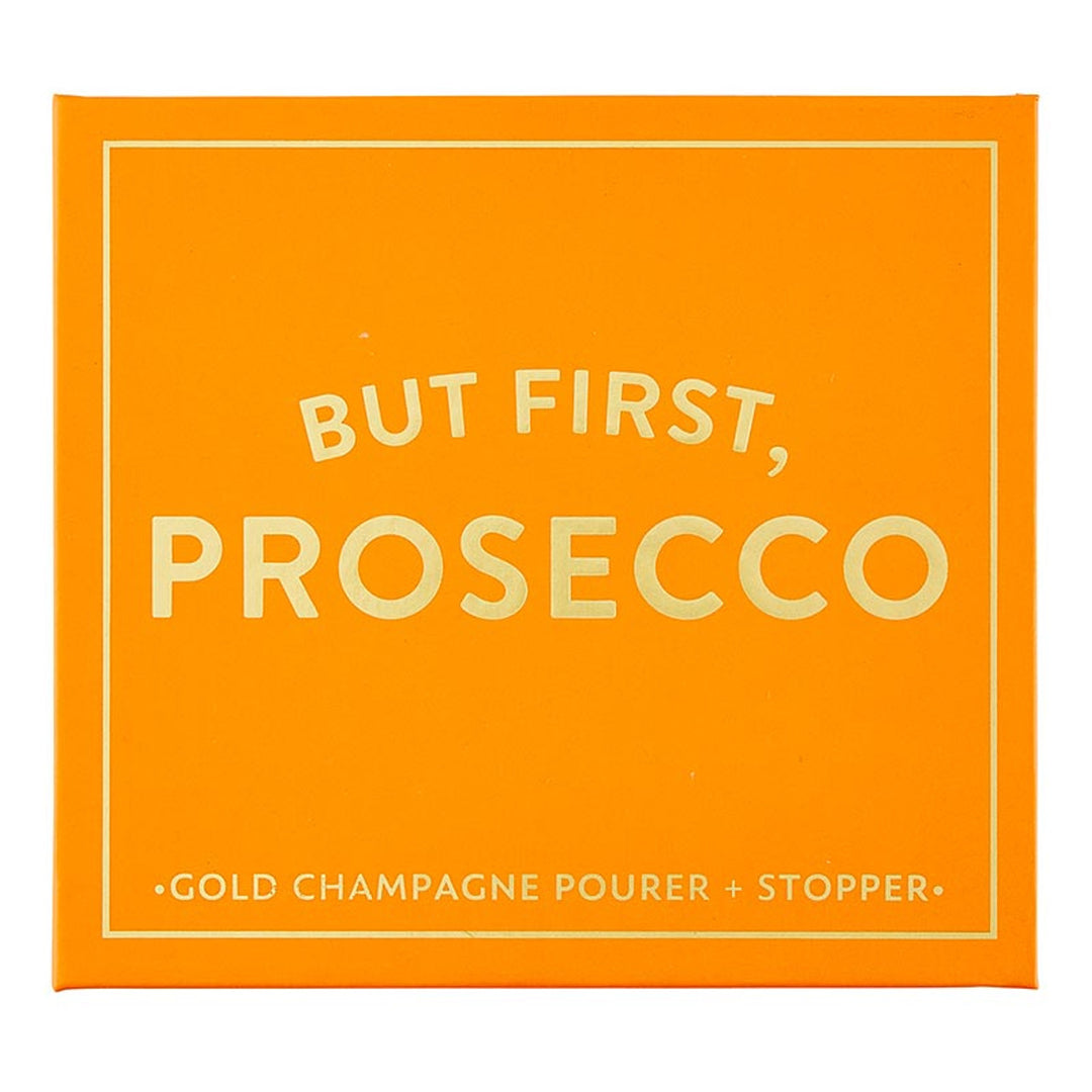 The "Champagne Stopper + Pourer Book Box - But First, Prosecco" is an orange box with magnetic book-style packaging. It features white text: "BUT FIRST, PROSECCO" and includes a gold champagne pourer and stopper for maintaining sparkling wines' freshness. Sizes available: Standard size for typical wine bottles.