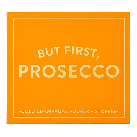The "Champagne Stopper + Pourer Book Box - But First, Prosecco" is an orange box with magnetic book-style packaging. It features white text: "BUT FIRST, PROSECCO" and includes a gold champagne pourer and stopper for maintaining sparkling wines' freshness. Sizes available: Standard size for typical wine bottles.