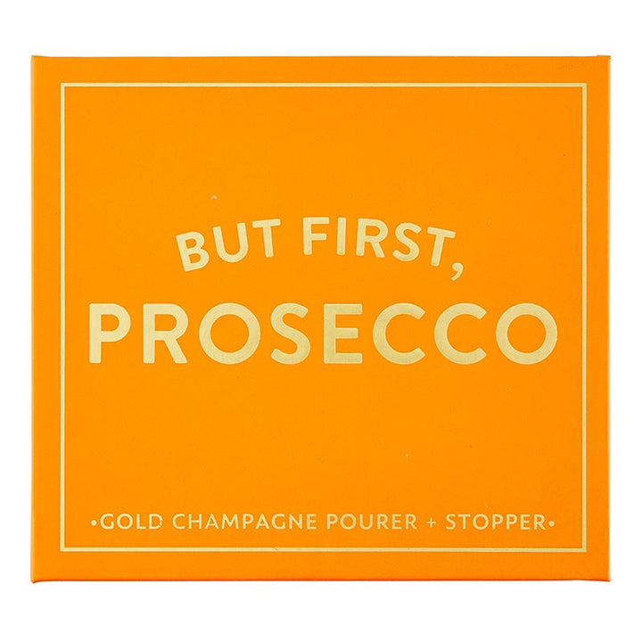 The "Champagne Stopper + Pourer Book Box - But First, Prosecco" is an orange box with magnetic book-style packaging. It features white text: "BUT FIRST, PROSECCO" and includes a gold champagne pourer and stopper for maintaining sparkling wines&