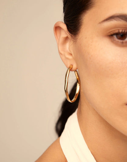 Large Open Hoop Earrings by UNOde50 shown; available in multiple sizes.
