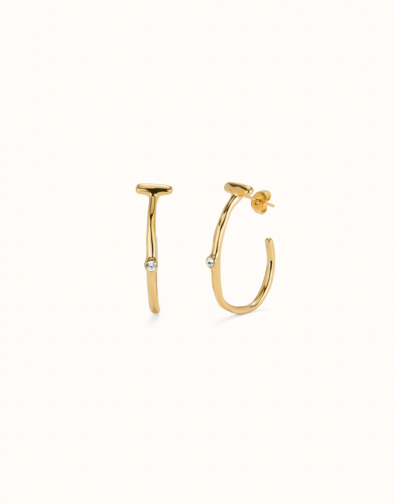 Hoop earrings with white topaz, crafted in 18K gold-plated metal with a modern design. Each earring has a small round white topaz gemstone at the center. Available sizes: small, medium, and large.