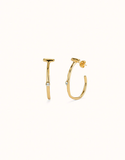 Hoop earrings with white topaz, crafted in 18K gold-plated metal with a modern design. Each earring has a small round white topaz gemstone at the center. Available sizes: small, medium, and large.