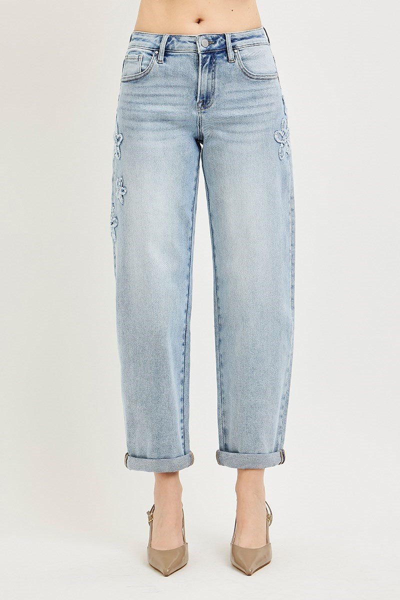 Light blue denim crop barrel jeans with floral patches and rolled cuffs. Available in sizes 24–32.