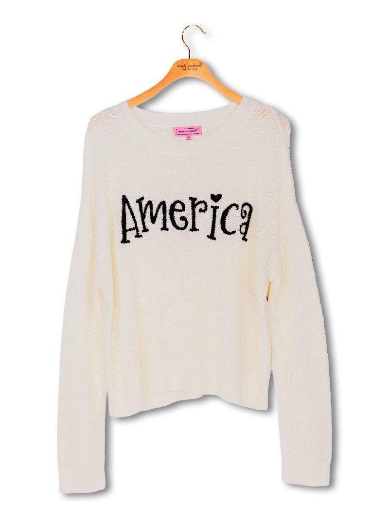 White relaxed-fit sweater with "America" in black embroidery on chest. Available in S, M, L, and XL.