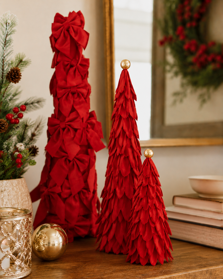 Three red velvet decor trees, one with bows and two with fabric petals, each with a gold sphere topper.
