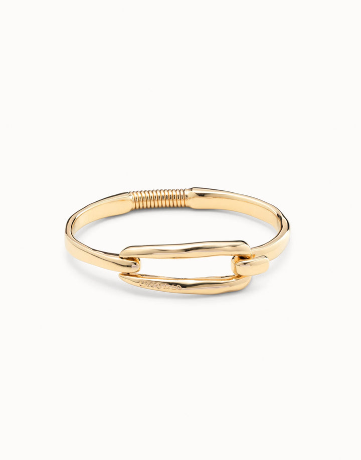 Gold-plated bangle bracelet by UNOde50 with buckle, handcrafted in Spain, featuring a hinged clasp and a rectangular curved bar at the center; available sizes: S, M, L.