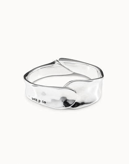The Minimalist Bangle Bracelet is silver-plated with a smooth, wavy design, overlapping closure, shiny finish, and subtle engraved inscription. Available in small, medium, and large sizes.