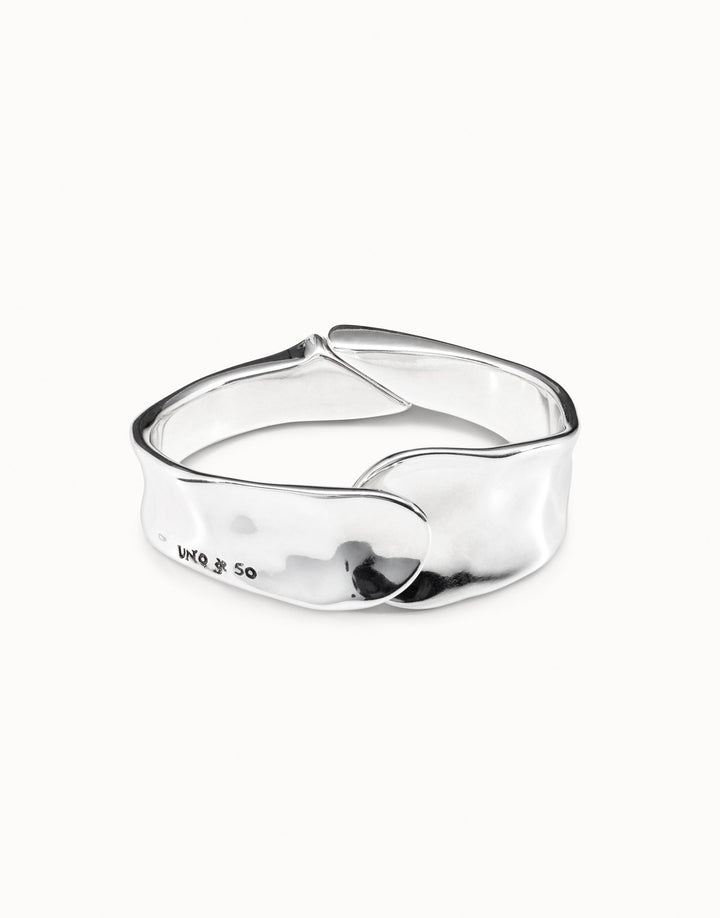 The Minimalist Bangle Bracelet is silver-plated with a smooth, wavy design, overlapping closure, shiny finish, and subtle engraved inscription. Available in small, medium, and large sizes.