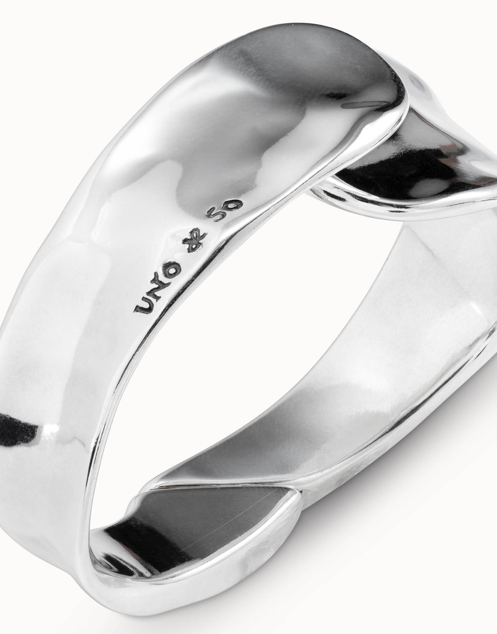 Shiny, silver, irregularly-shaped minimalist bangle bracelet, engraved with "UNO de 50" and a small symbol on the inner surface; handcrafted in Spain. Available in multiple sizes.