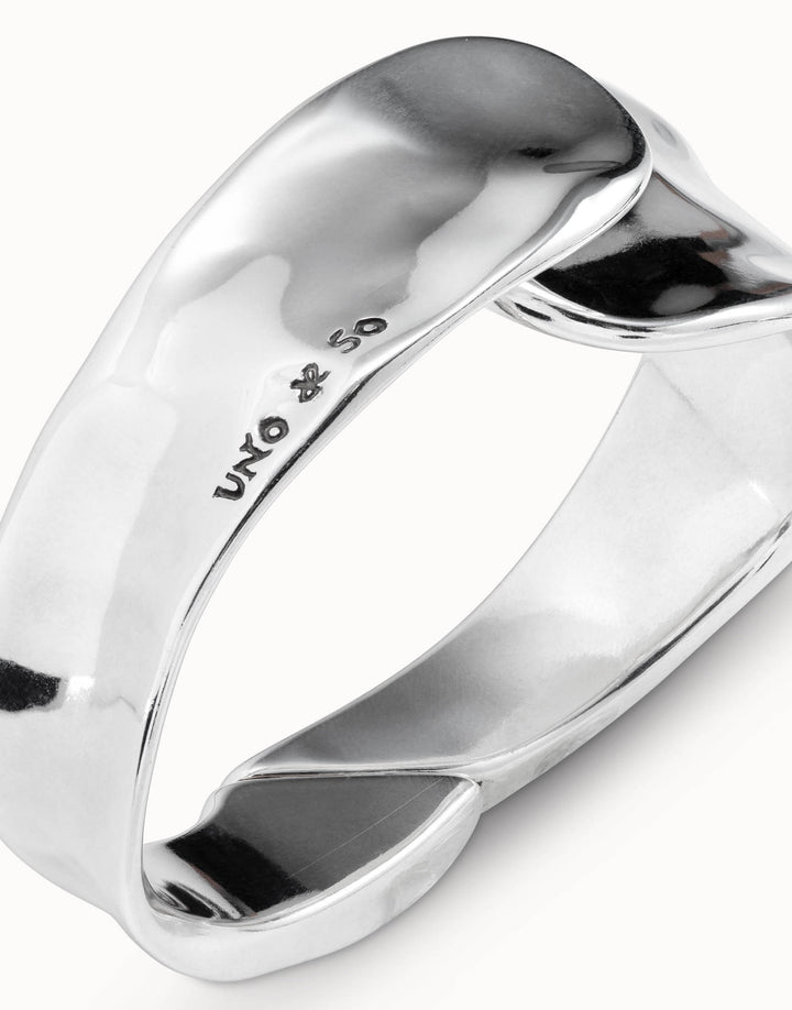 Shiny, silver, irregularly-shaped minimalist bangle bracelet, engraved with "UNO de 50" and a small symbol on the inner surface; handcrafted in Spain. Available in multiple sizes.