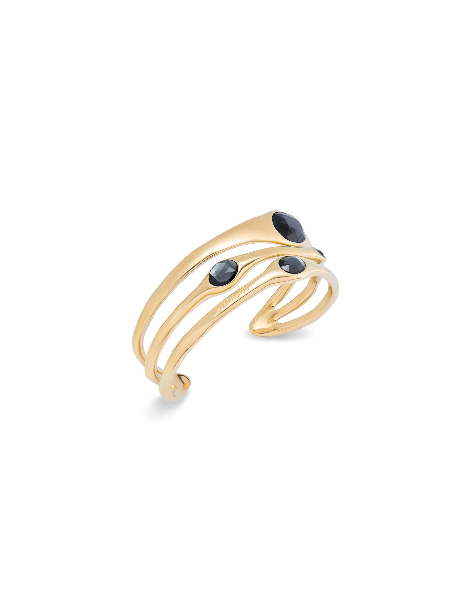 Modern bangle bracelet in 18k gold with three overlapping bands, each set with a round dark crystal; smooth curves, polished finish. Available in sizes S, M, and L.