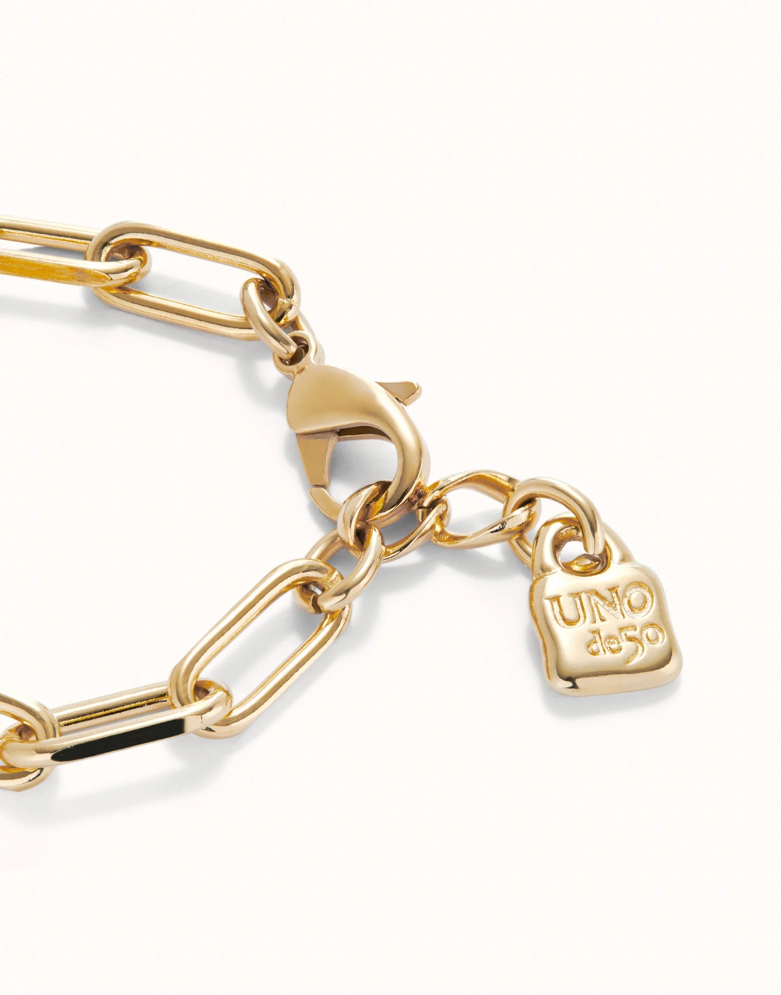 Gold Paper Clip Link Bracelet with Padlock, elongated 18K gold-plated links, lobster clasp, small square "UNO de 50" engraved padlock charm; available in S, M, and L sizes.