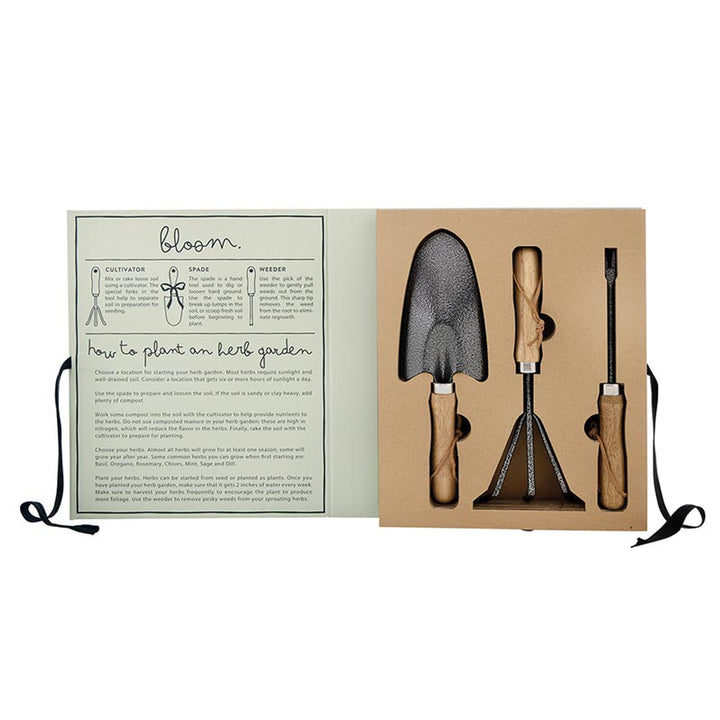 The Garden Tool Set Book Box - Live Love Grow includes a trowel, rake, and weeder made from Canton Steel with beech wood handles. The lid features planting instructions and illustrations.