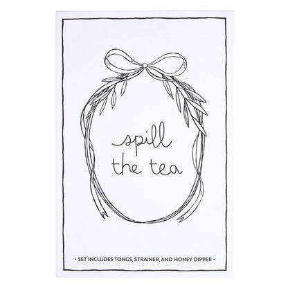 The "Tea Essential Book Box - Spill The Tea" is a charming set featuring a tea-themed print with black and white wreath illustration. It includes tea bag tongs, a tea infuser strainer, and a honey dipper. Available sizes: N/A.