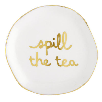 Round white ceramic tea bag holder with uneven edges, gold rim, and "spill the tea" in cursive gold lettering. Size: Not specified.