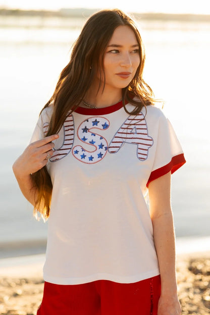 Sequin "USA" White Top with red trim on sleeves and collar, patriotic sequined design. Sizes: XS-XL.