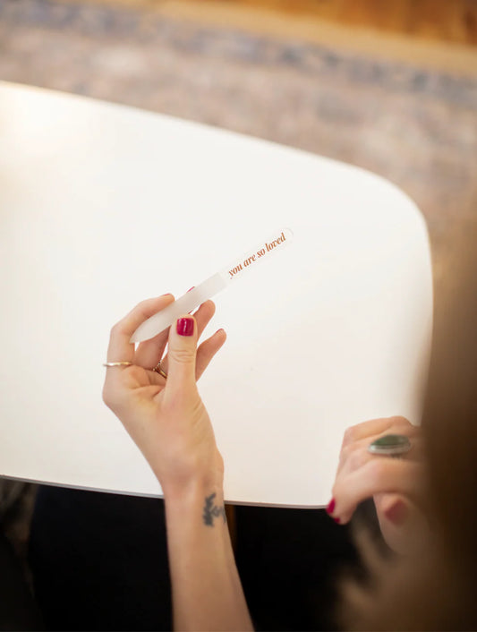'You are so loved' glass nail file, shown shaping nails. Available in 5-inch and 3.5-inch sizes.