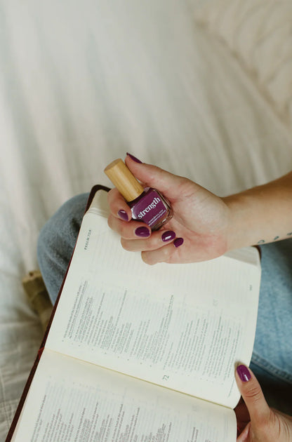 A bottle of 'strength' violet purple vegan nail polish shown; available in 10ml and 15ml sizes.