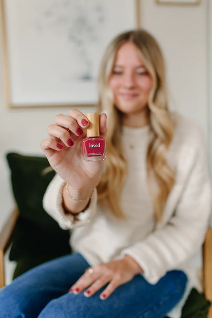 ‘Loved’ rose red nail polish bottle shown. Available in 10ml and 15ml sizes. Bold rose red color.