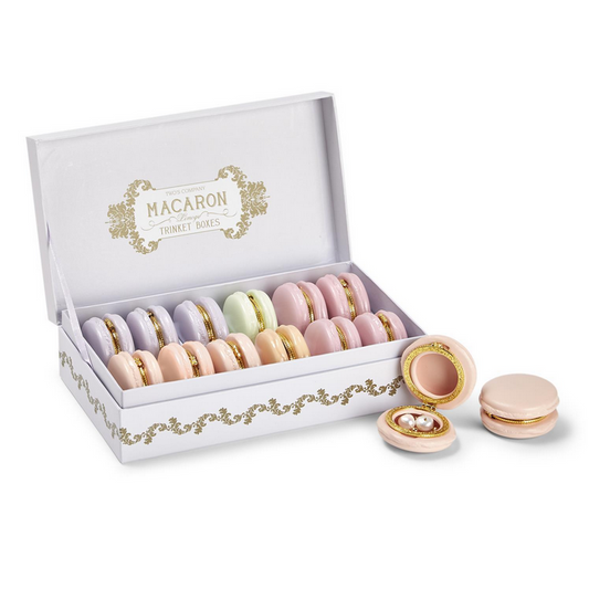 The product is a collection of ceramic Macaron Limoge trinket boxes, designed to resemble pastel-colored macarons. They come arranged in a white box with golden floral accents. Some trinket boxes are displayed open. The size of the individual box varies; further details would be specific to each product.