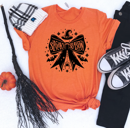 Orange Bow Spooky Season Graphic Tee featuring a witch hat design. Available in sizes S, M, L, XL.