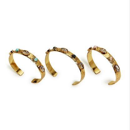 Three adjustable cuffs featuring textured, hammered design with natural stone accents in turquoise, black, and pink. Available in one-size-fits-all adjustable fit.