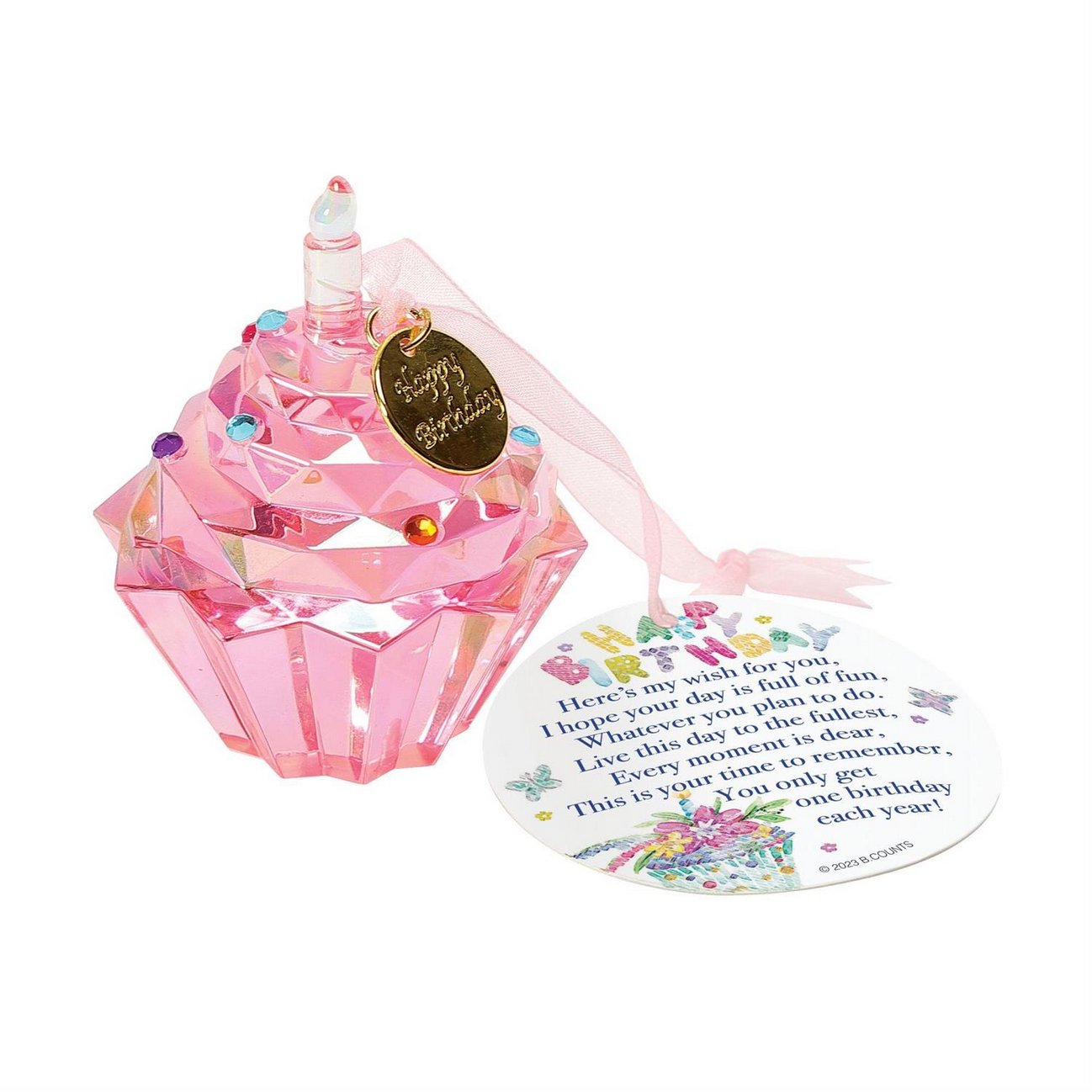 The Enesco Facet Collection Happy Birthday Cupcake Ornament is a pink, crystal-like cupcake-shaped decoration with a gold tag inscribed "Happy Birthday," small colorful gems, and a pink ribbon. It comes with a circular card featuring a birthday message and vibrant illustrations. Available in one size.