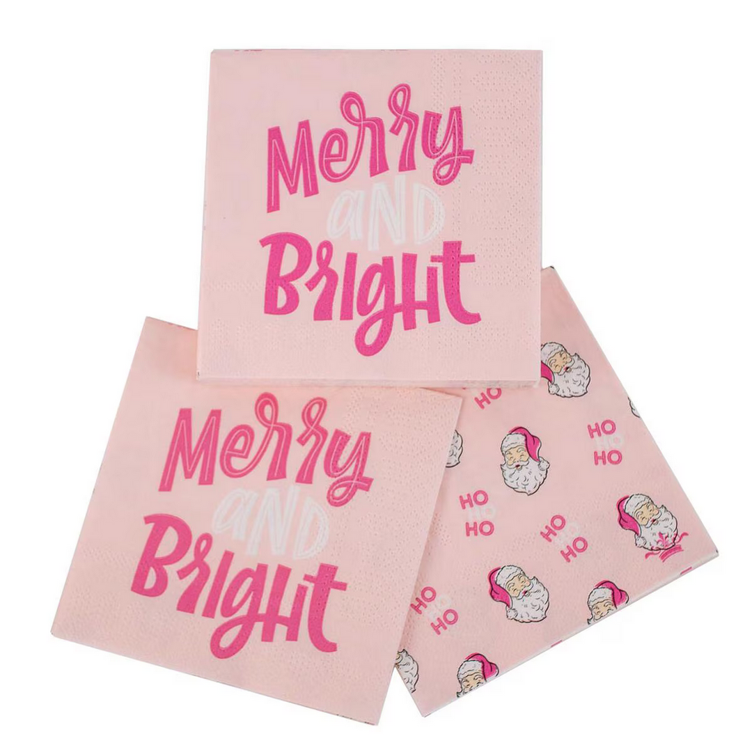 Three Merry &amp; Bright cocktail napkins in light pink. Two napkins feature “Merry and Bright” text in pink and white; one features Santa Claus and “HO” illustrations. Available in cocktail size.