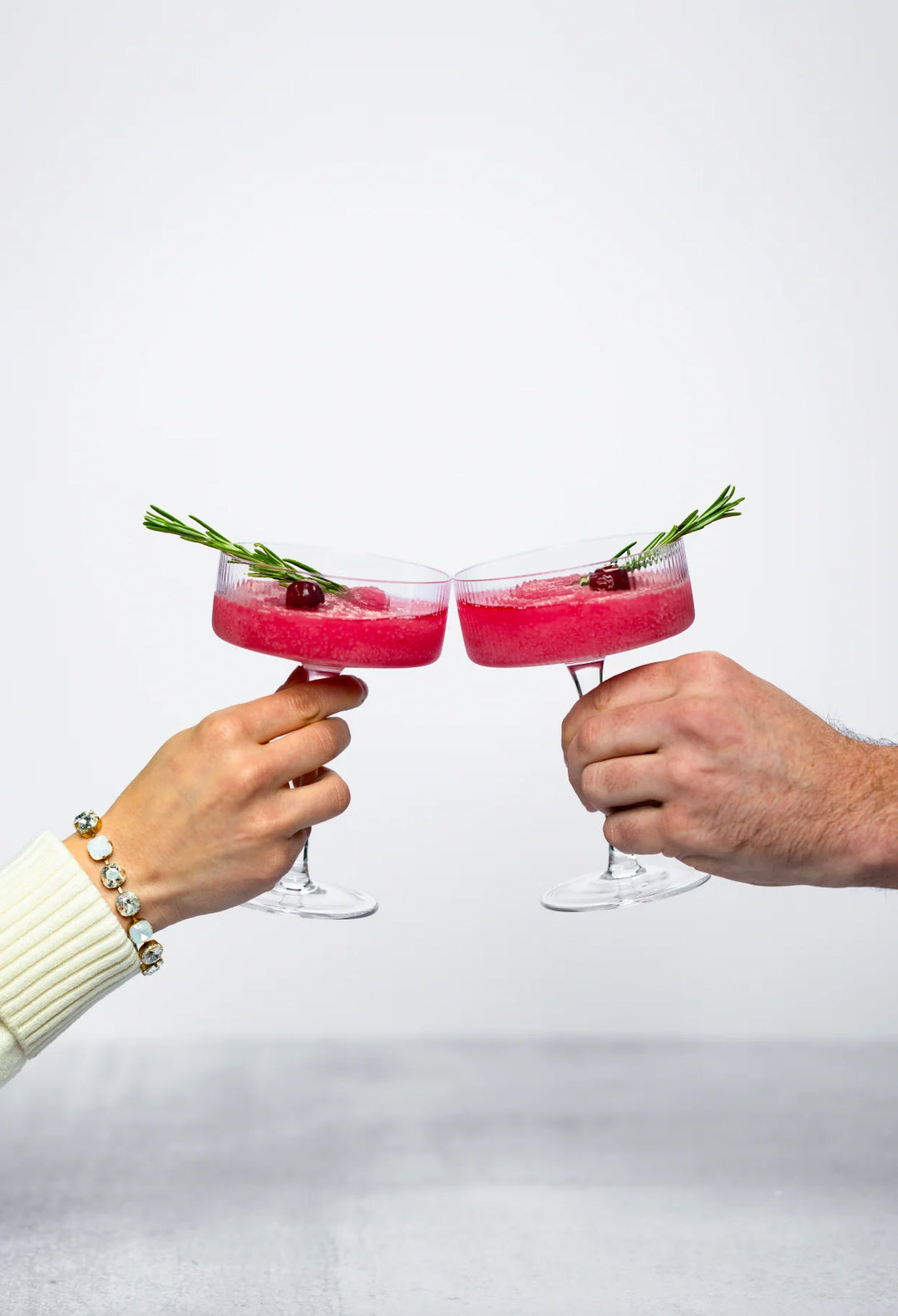Jingle Juice 10 oz. d’marie Drink Mixes pink slushy garnished with cranberries and a rosemary sprig.