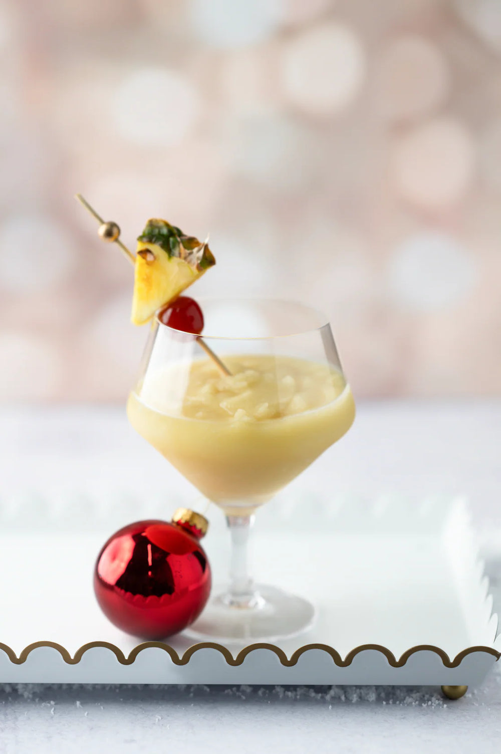 10 oz. Snowball Cocktail | d’marie Drink Mixes in a stemmed glass with a pineapple wedge and a cherry.