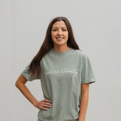 Sage green Eyes on Eternity Tee with "eyes on eternity" in white script; available in sizes S-XXL.