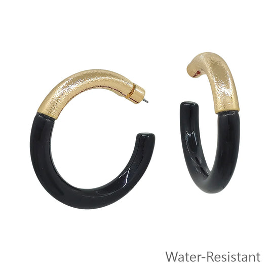Gold-toned and glossy black resin hoop earrings with a contemporary design. Available sizes: small, medium, large. Water-resistant.