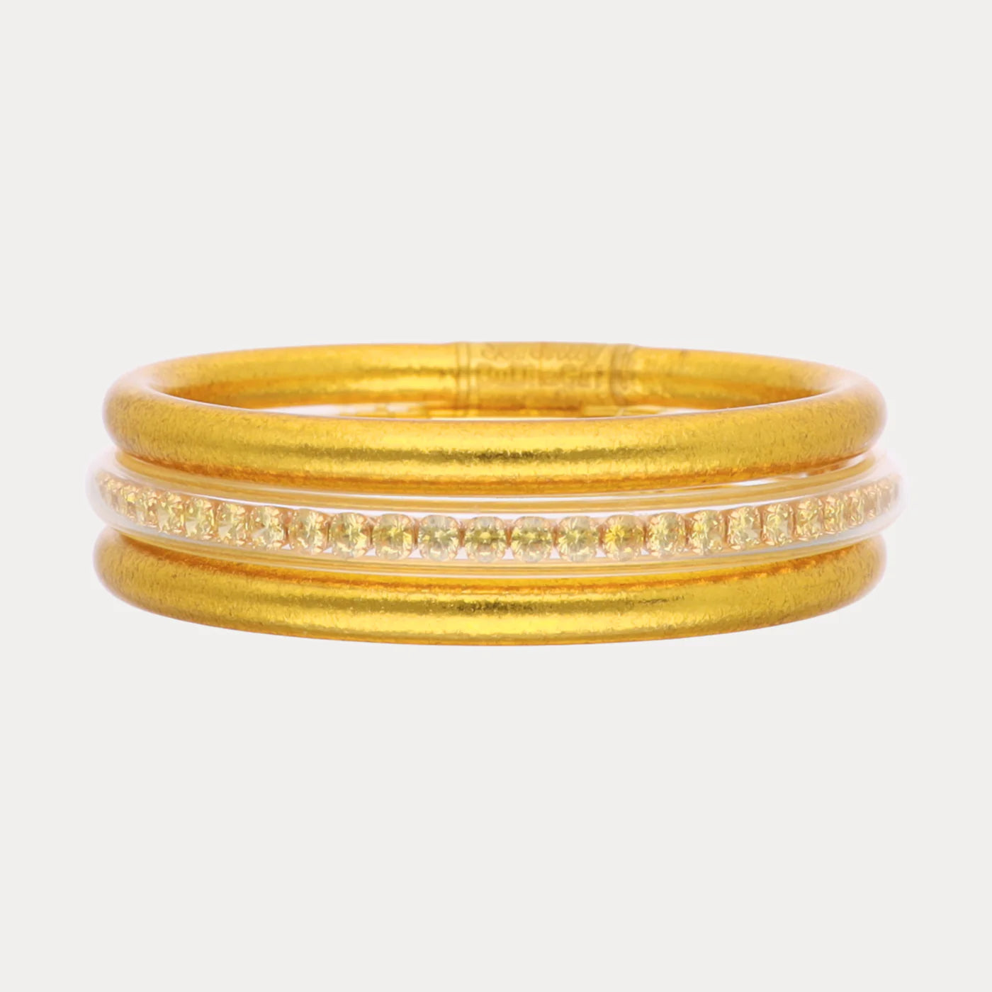 Gold ring with matte finish, three parallel bands, center band set with small clear gemstones. Available in sizes 5-9.