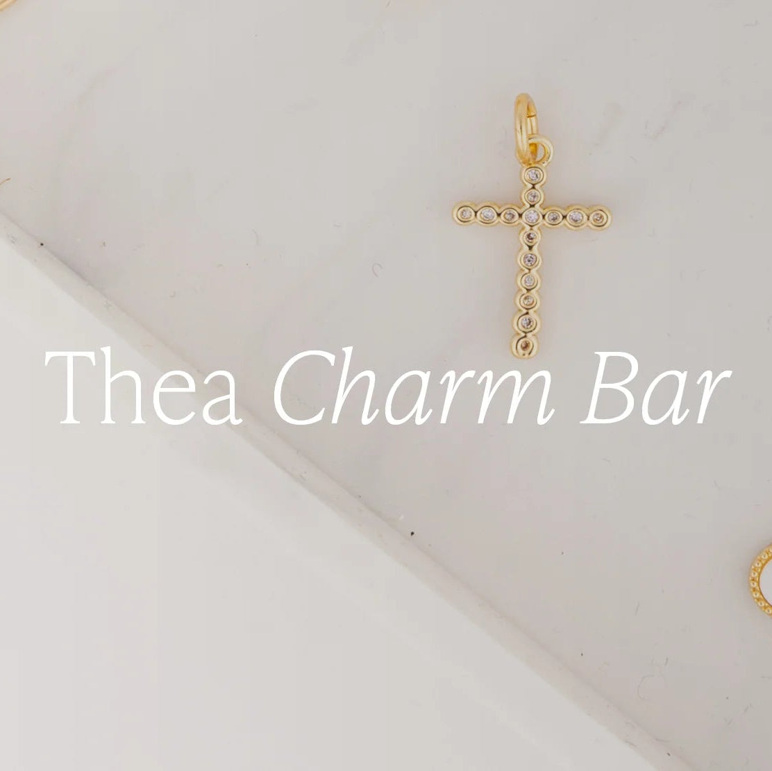 A delicate 18k gold-plated cross pendant with small circular accents, available in multiple sizes. Customizable as part of the Thea Charm Bar collection.