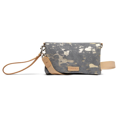 Small gray Uptown Crossbody, Jagger, with gold splatter design, tan leather wristlet strap, and front tan leather Consuela patch. Available in one compact size.